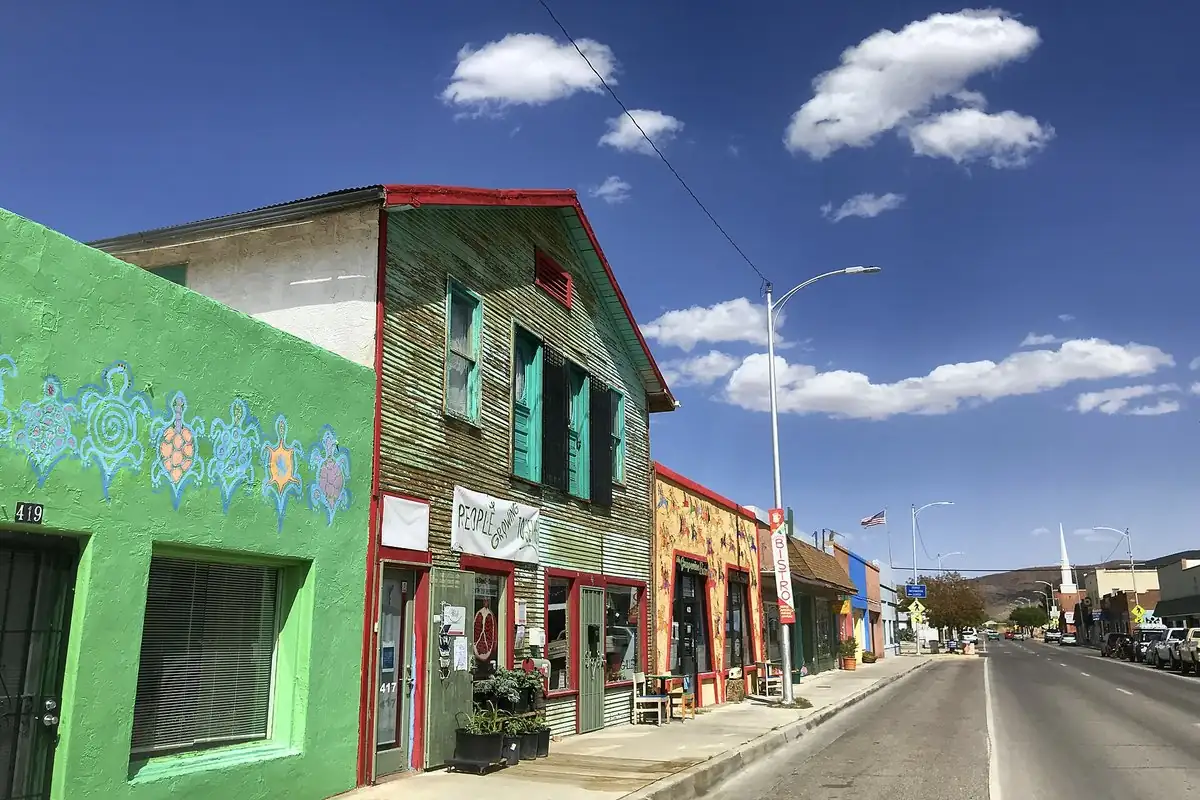 Brightly painted old storefronts, one green with turtle murals, on Broadway in Truth or Consequences, New Mexico, a town with one of the weird town names on this page.